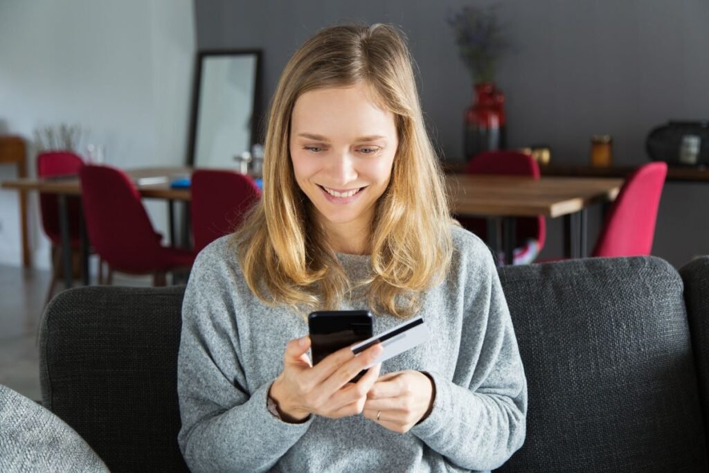 young woman looking at her mobile with credit card in have about to purchase an item on an online shop